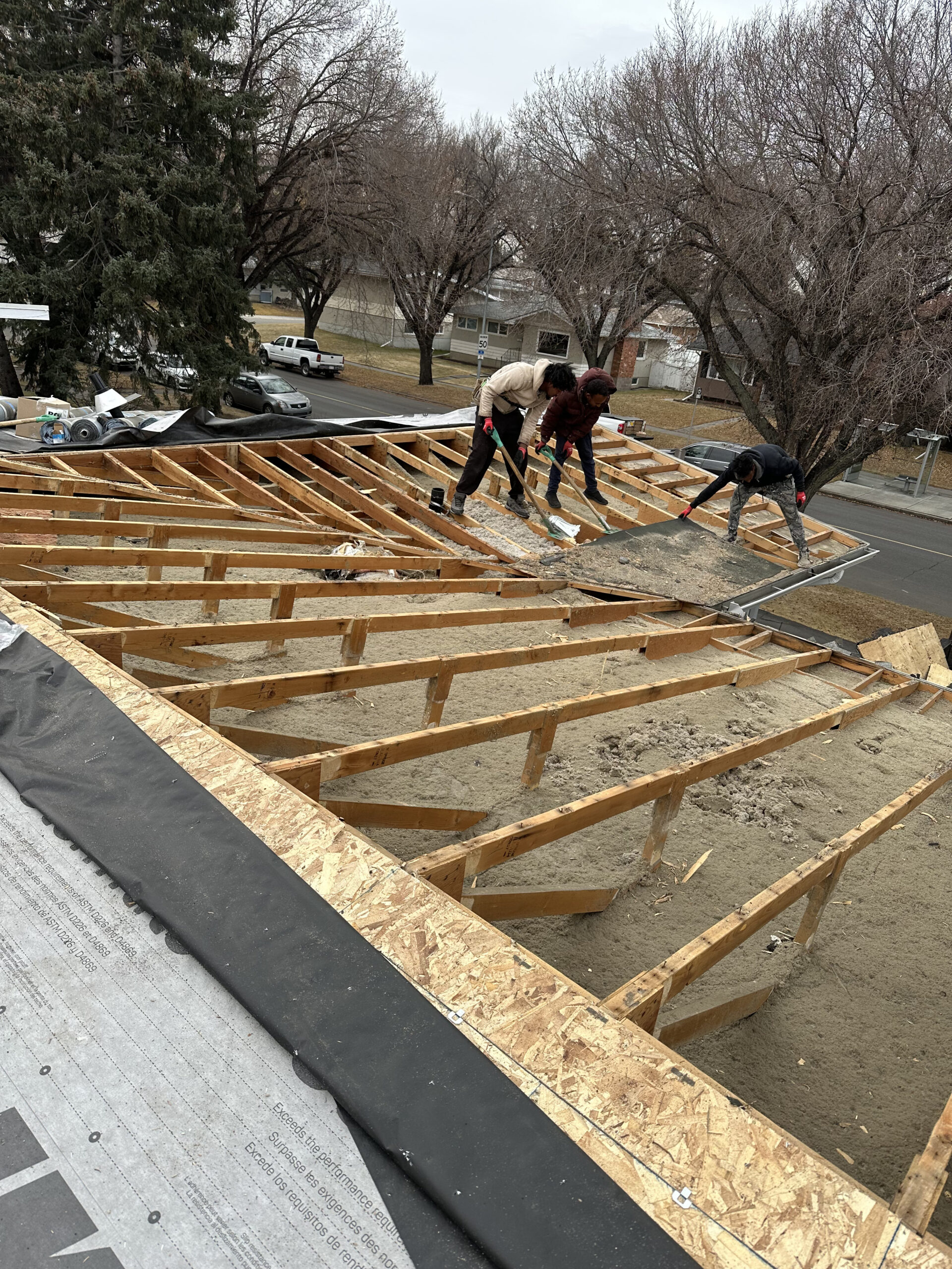 Roofing crew removing a damaged flat roof deck in Calgary